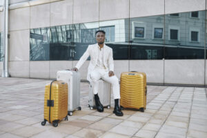 Teko Modise in white suit seated next to Samsonite products