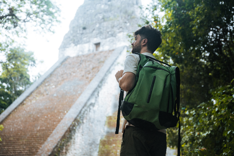 man in green ecodriver backpack standing staring at the sky